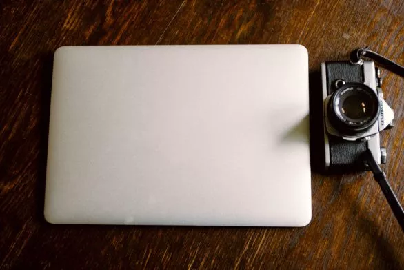 Closed macbook and a vintage camera
