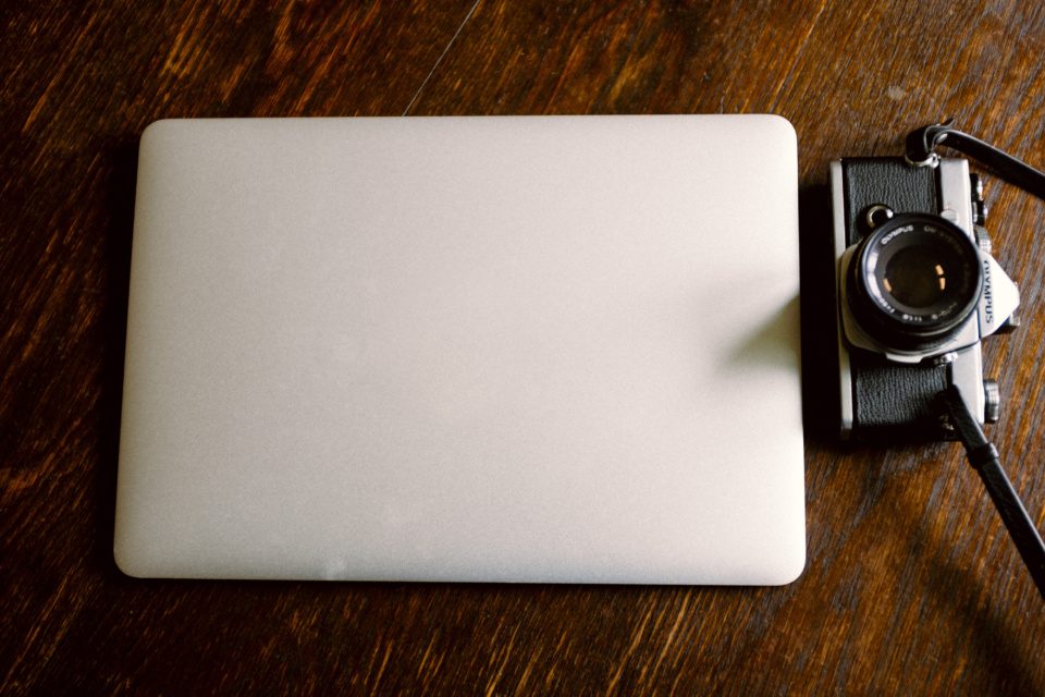 Closed macbook and a vintage camera
