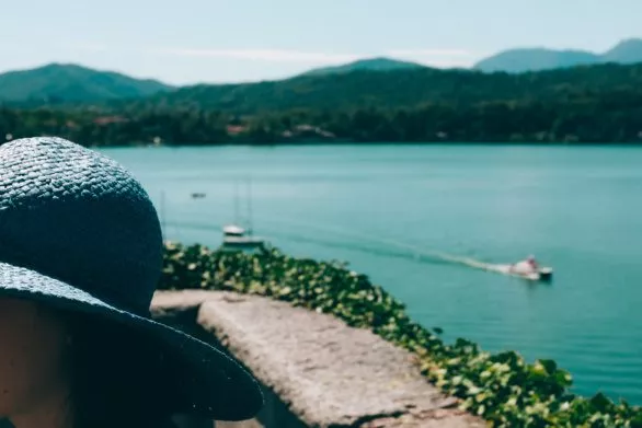 Girl in blue hat in front of mountain lake in Italy