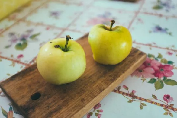 Two fresh apples on a wooden kitchen board