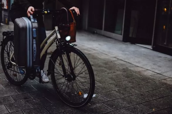 A cyclist with a suitcase in her hand