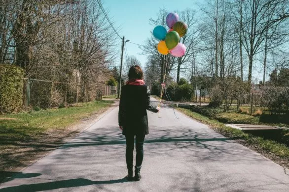 Young adult with colorful baloons on the street