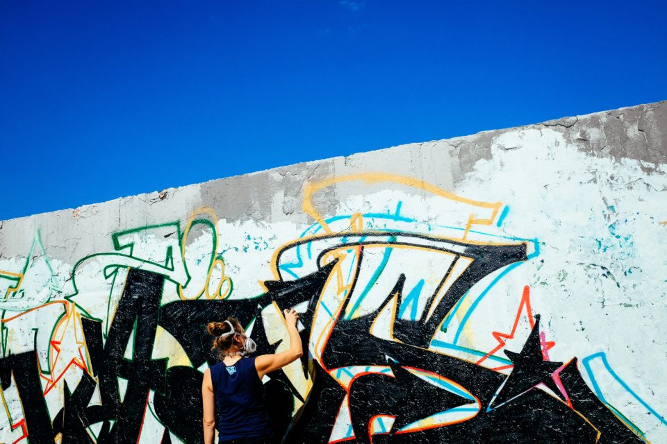 Graffiti artist paints on Berlin wall