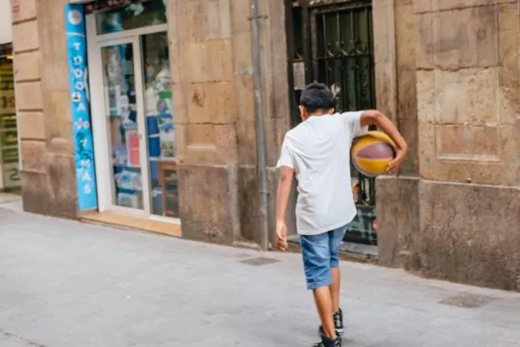 boy carries a ball on a street