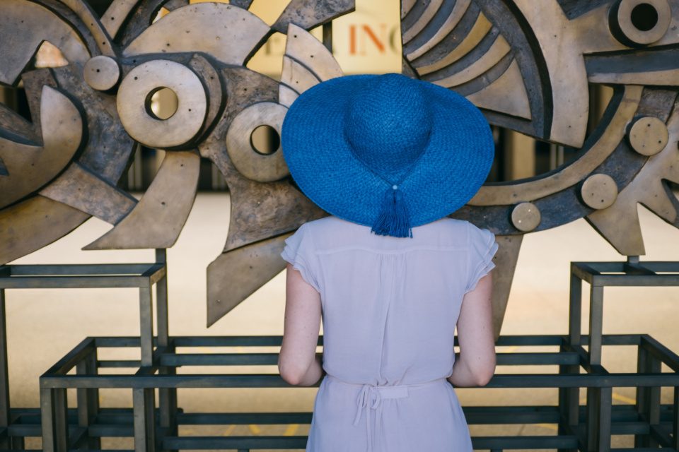 Young woman in blue hat looks at the art installation