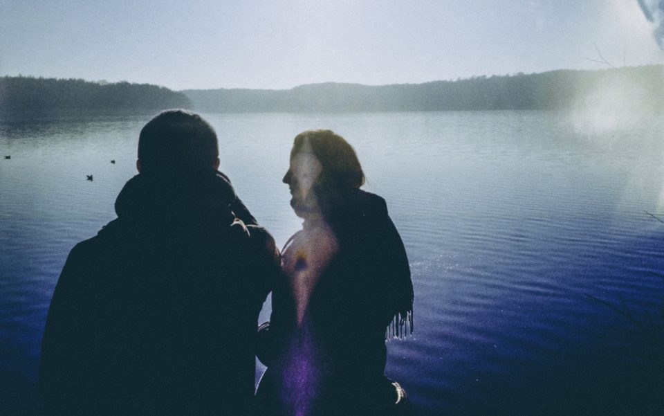 Two people standing by the lake in bright blue light