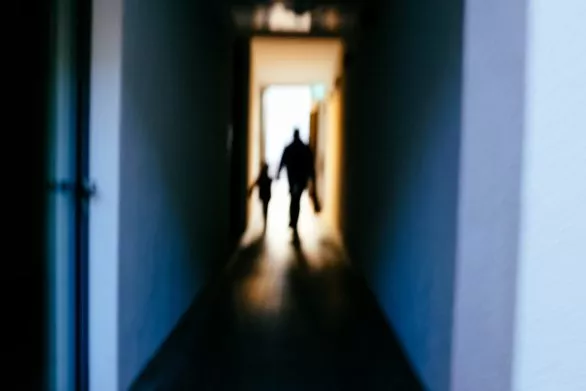Silhouettes of a child and an adult going towards the light