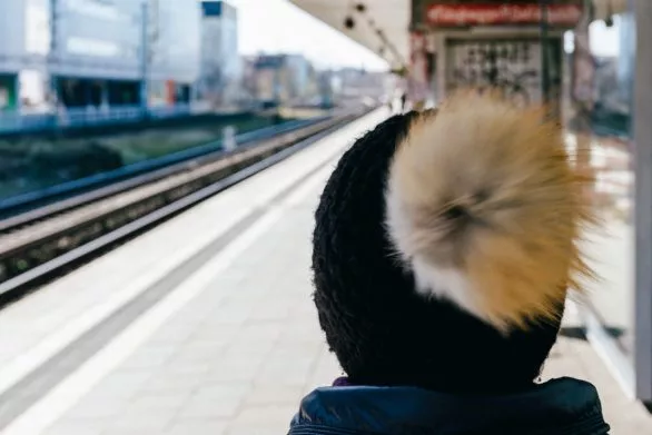 A young woman with a pompom hat at the train station