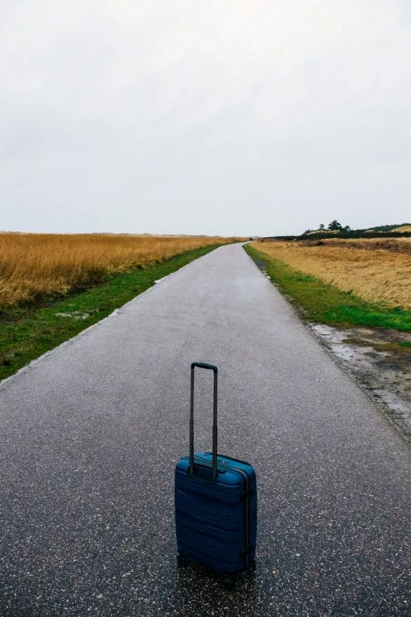 Blue suitcase on an empty field road