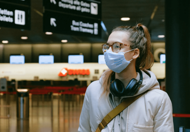 Woman Wearing a Face Mask at the Airport [Free Mockup Generator]