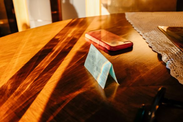 Phone and sticky note on the table in sunlight