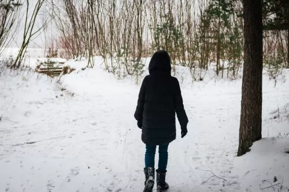 A girl walks to the sea through a winter forest
