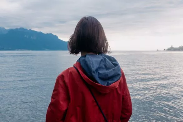 Young woman in red coat in front of Lake Geneva in Switzerland