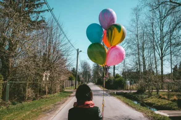 Young woman with balloons on an empty road
