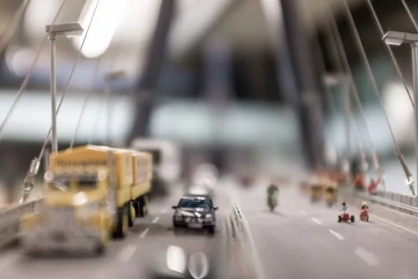 Miniature cars go over the toy bridge