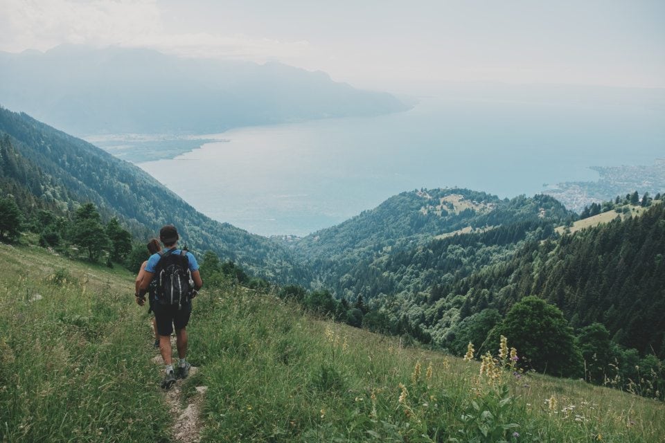Hikers go down the mountain slope to Lake Geneva
