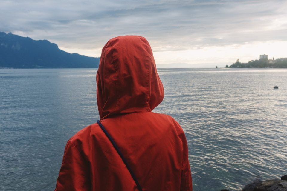 Young woman in a rain coat in front of Lake Geneva in Switzerlan