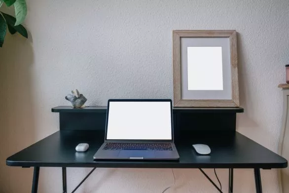 Laptop computer mockup with framed poster artwork on black table