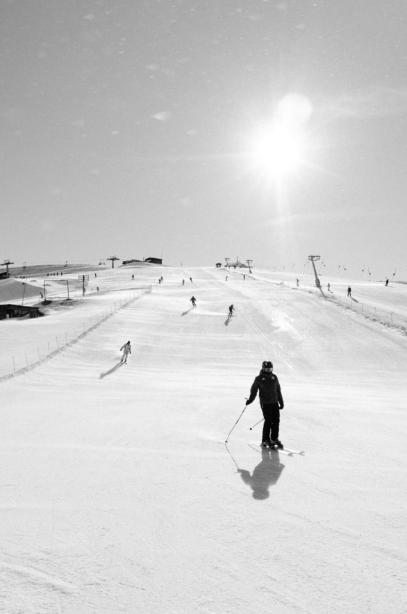 Skiers Descend a Snowy Slope Under a Bright Sun in Black and Whi