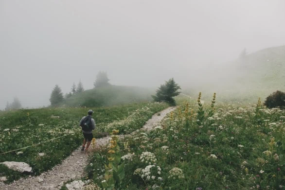 Hiker on mountain trails in thick clouds