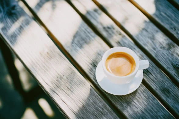 Cup Of Coffee Sitting On Wooden Table In A Bright Outdoor Enviro