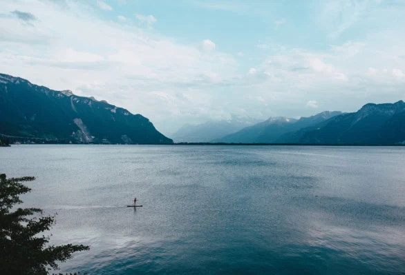 Single Paddleboarder on Lake Geneva with Majestic Mountain Views