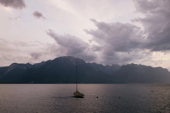 Moody Sunset Over Lake Geneva with a Lone Yacht and Alpine Backd