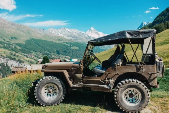 Vintage 4x4 Jeep Parked in the Swiss Alps with a Scenic Mountain