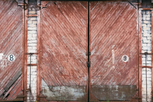 Old Weathered Wooden Garage Doors with Brick Wall and Painted Nu