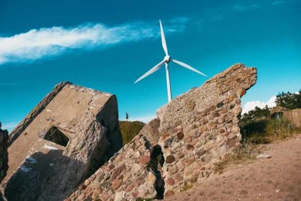 Person Among Ruins and Wind Turbine at Karosta Beach, Liepaja, L