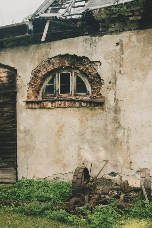 Old arched window on a weathered rural manor building