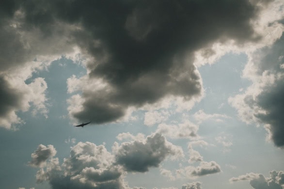 Dramatic storm clouds with bird silhouette against blue sky